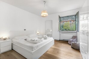 A modern bedroom with a large bed, bedside lamps, a window with a view, and a radiator. - Margherita Apartment - Lake and Mountain Views, Malcesine, Italy (Malcesine)