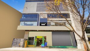 A modern building with a storefront, large windows, and a tree in front. - Super Townhouse Oak DLF Newtown (Bengaluru)