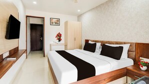 A hotel room with a bed, bedside table, nightstand, wardrobe, and a television on the wall. - Super Townhouse Oak DLF Newtown (Bengaluru)