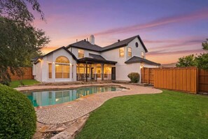 A two-story house with a swimming pool, a covered patio, and a wooden fence. - Modern Oasis with Large Pool + Ping-Pong Sleeps 14 (McKinney)