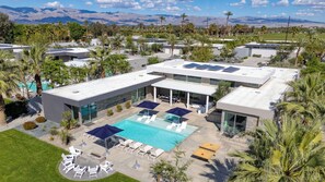 A modern resort with a swimming pool, lounge chairs, and a view of mountains. - Avantstay Polo Villa Halo Pickleball, Putting Green Sleeps 28 (La Quinta)