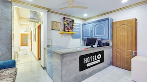 Una reception d'albergo con un cartello, un computer e una porta in legno.