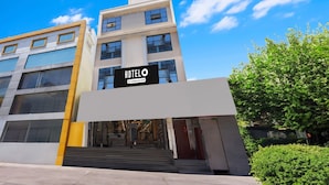 Un moderno edificio di un hotel con un cartello ben visibile, diversi piani e una scalinata che conduce all'ingresso.