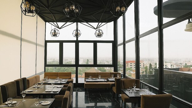 A restaurant with tables and booths, large windows, and a city view. - Modern East Legon Studio with Private Balcony - Accra (Accra)