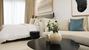 A modern hotel room with a bed, sofa, coffee table, and a painting on the wall. - Modern East Legon Studio with Private Balcony - Accra (Accra)