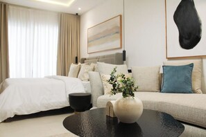 A modern hotel room with a bed, sofa, coffee table, and a painting on the wall. - Modern East Legon Studio with Private Balcony - Accra (Accra)