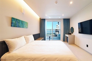 Une chambre d’hôtel moderne avec un grand lit, un téléviseur à écran plat, un balcon avec vue et un tableau au mur.