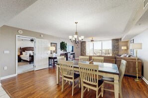 A spacious living area with a dining table, chairs, a sofa, and a TV. - Waterfront Escape at Yacht Club Villas | Pool, Golf & Barefoot Landing Nearby (North Myrtle Beach)