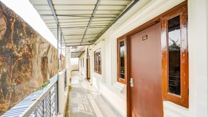 A corridor with a metal roof, a wooden door, and a marble floor. - Deluxe Hotel Raj Shree (Lucknow)
