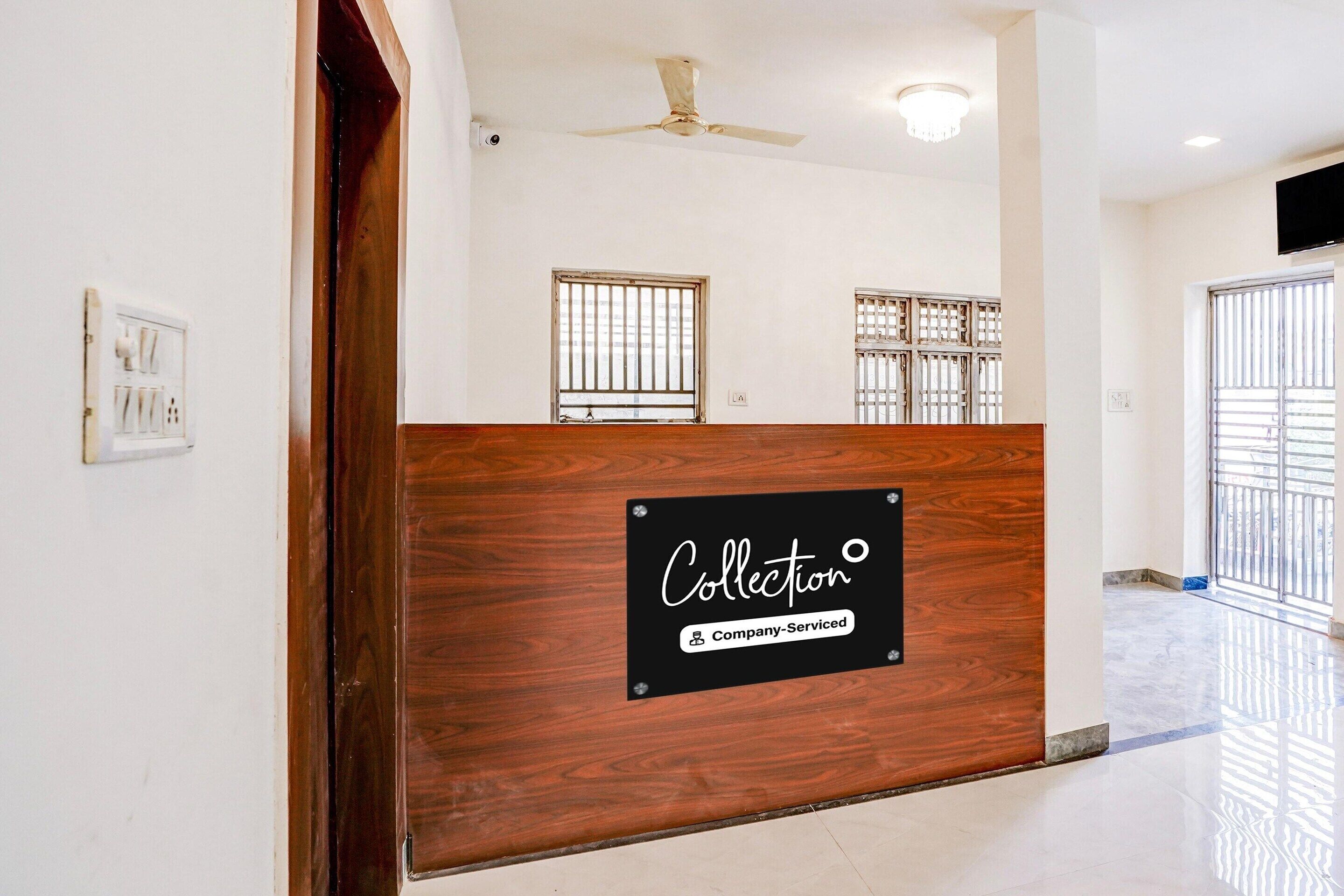 A reception area with a wooden reception desk, a ceiling fan, and barred windows.