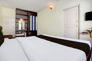 A hotel room with a bed, a desk, a mirror, a wardrobe, and a television.