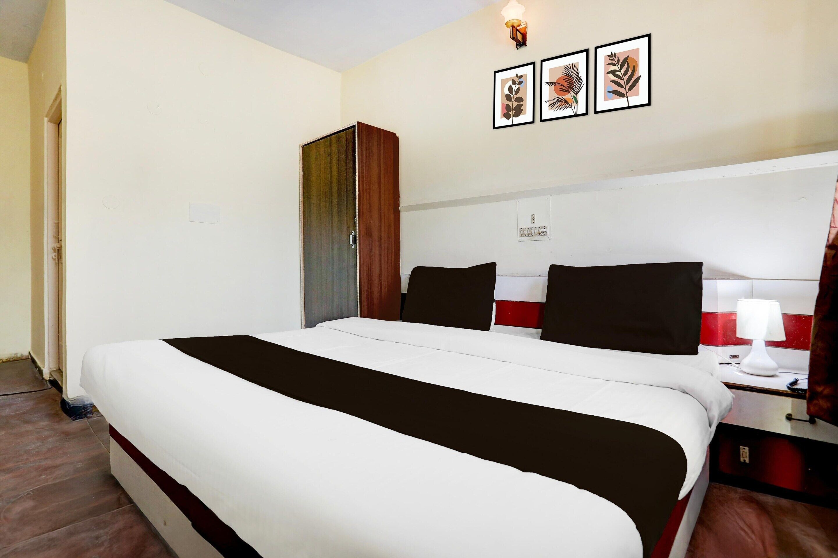 Ein Hotelzimmer mit Bett, Nachttisch, Lampe und Schrank.