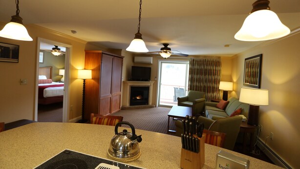 Habitación de hotel con kitchenette, comedor, sala de estar con chimenea y vista al exterior.