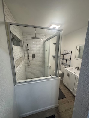 A bathroom with a glass shower enclosure, a white sink, and a mirror. - Charming 3-bedroom house with AC in El Paso (El Paso)
