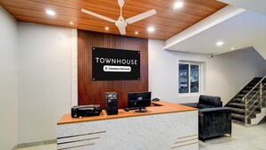 Uma receção com uma placa a indicar 'TOWNHOUSE Company-Serviced', um ventilador de teto e uma escadaria.