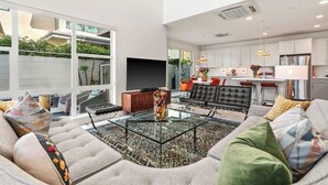 A modern living room with a glass coffee table, a sofa, and a television. - "Good Times" at The Vibe - Private Spa, Views (Palm Springs)