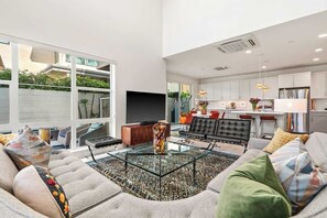 Uma sala de estar moderna com uma mesa de centro de vidro, um sofá e uma televisão.
