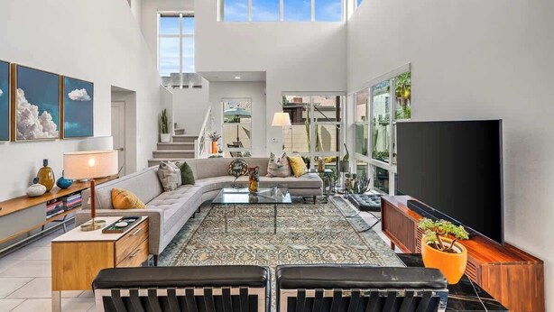 A spacious living room with a large flat-screen TV, a sofa, a coffee table, and a potted plant. - "Good Times" at The Vibe - Private Spa, Views (Palm Springs)
