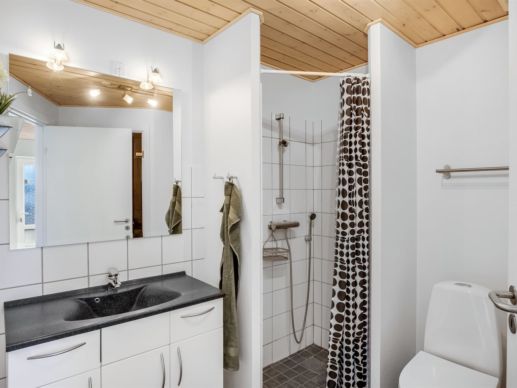 Een badkamer met een wastafel, spiegel, douche en toilet.