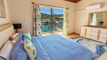 Un dormitorio con cama, cómoda, espejo y vista a una piscina y montañas.