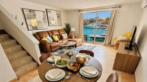 Zona pranzo con tavolo imbandito per quattro, divano e vista sul porto turistico.