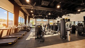 Una palestra con tapis roulant, macchinari per pesi e un'ampia finestra.
