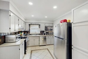 A modern kitchen with white cabinets, stainless steel appliances, and a tiled floor. - Charming home w/wifi, outdoor patio, and in the heart of Savannah (Savannah)