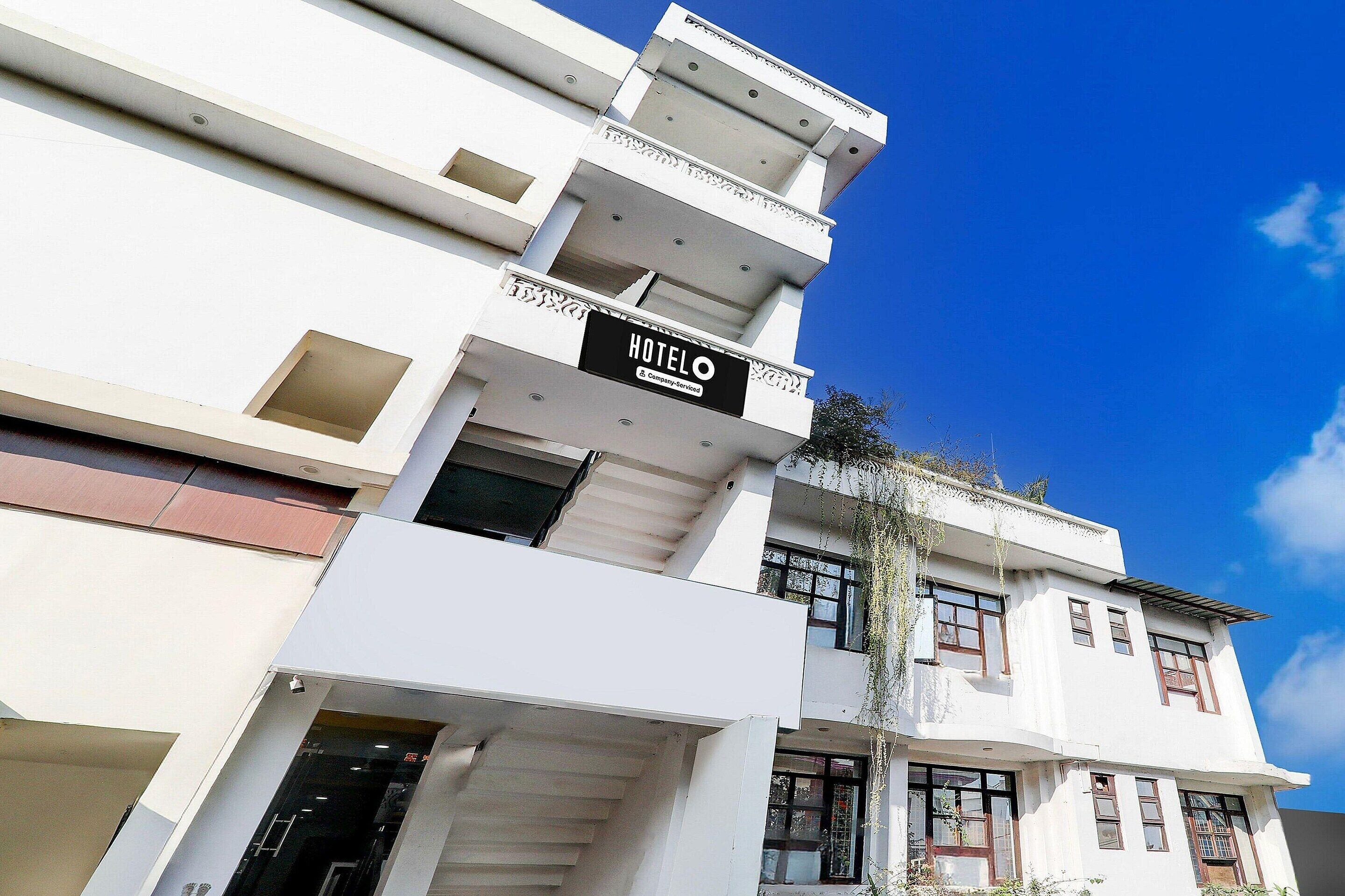 A multi-story hotel with a prominent 'HOTEL' sign, balconies, and a clear blue sky.