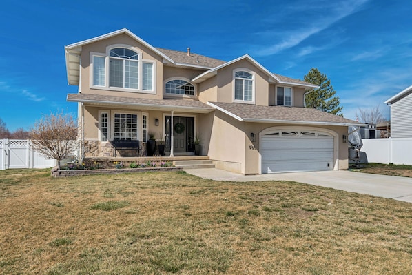 A two-story house with a garage, a front porch, and a landscaped yard.