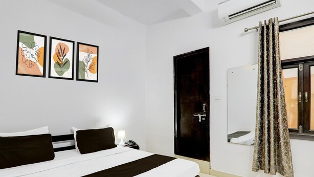 A hotel room with a bed, a nightstand, a phone, and framed artwork on the wall. - Super Hotel O Indira Nagar (Lucknow)