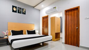 A modern hotel room with a large bed, wooden wardrobe, and an air conditioning unit. - Premium Townhouse Shamshabad Near Airport (Hyderabad)