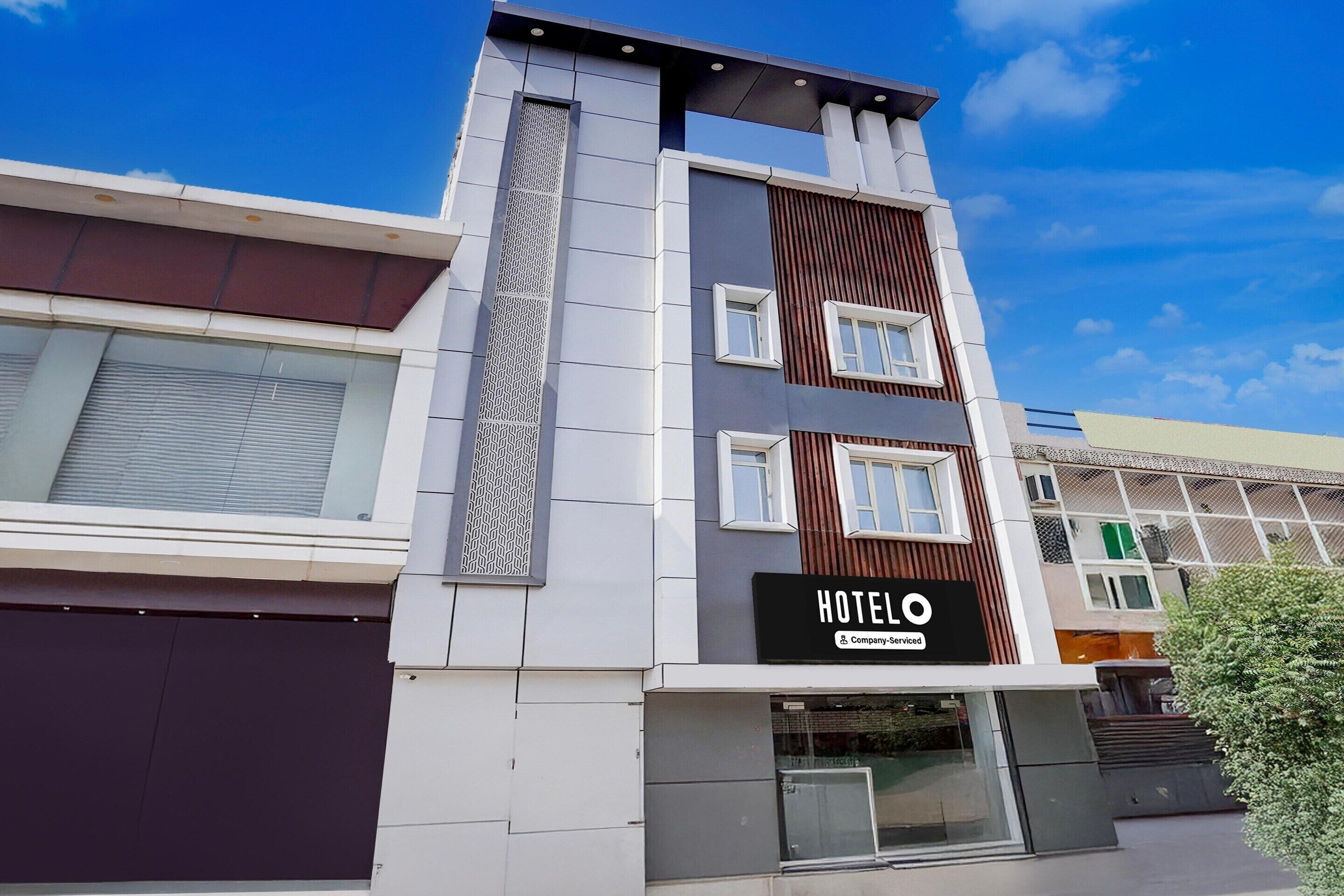 A modern hotel building with a prominent 'HOTELO' sign, large windows, and a clean facade.