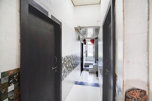 A hallway with a dark door, tiled walls, and a staircase leading to an upper level. - Deluxekrishna Janam Bhoomi (Mathura)