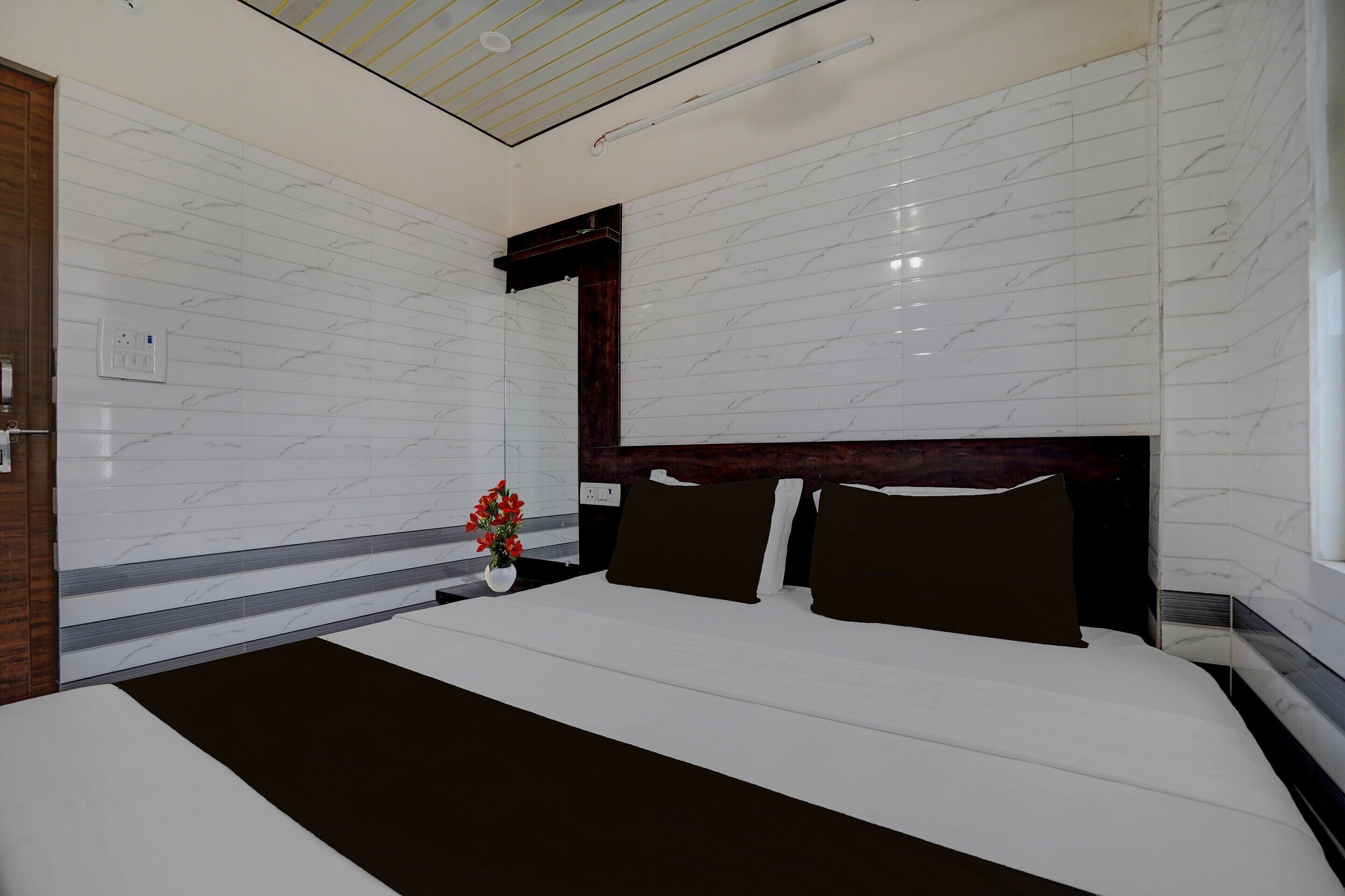 A modern hotel room with a large bed, marble walls, a wooden headboard, and a small potted plant.