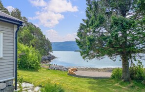 A lakeside property with a house, a dock, and a large tree.