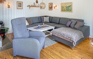 A modern living room with a grey sectional sofa, a matching armchair, a white coffee table, and a wooden floor.