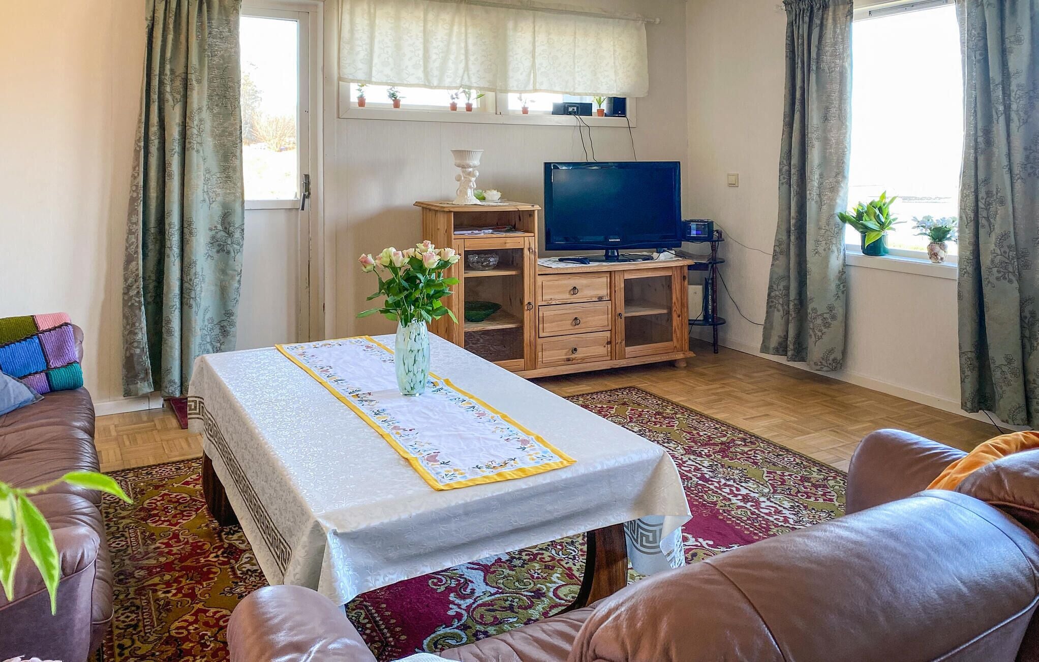 Uma sala de estar com sofá, mesa de centro, televisão e um aparador de madeira.