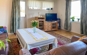 A living room with a sofa, a coffee table, a TV, and a wooden cabinet. - 3 bedroom awesome home in Gjemnes (Gjemnes)
