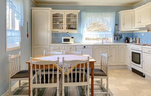 A kitchen with white cabinets, a dining table with chairs, a microwave, and an oven. - 3 bedroom awesome home in Gjemnes (Gjemnes)