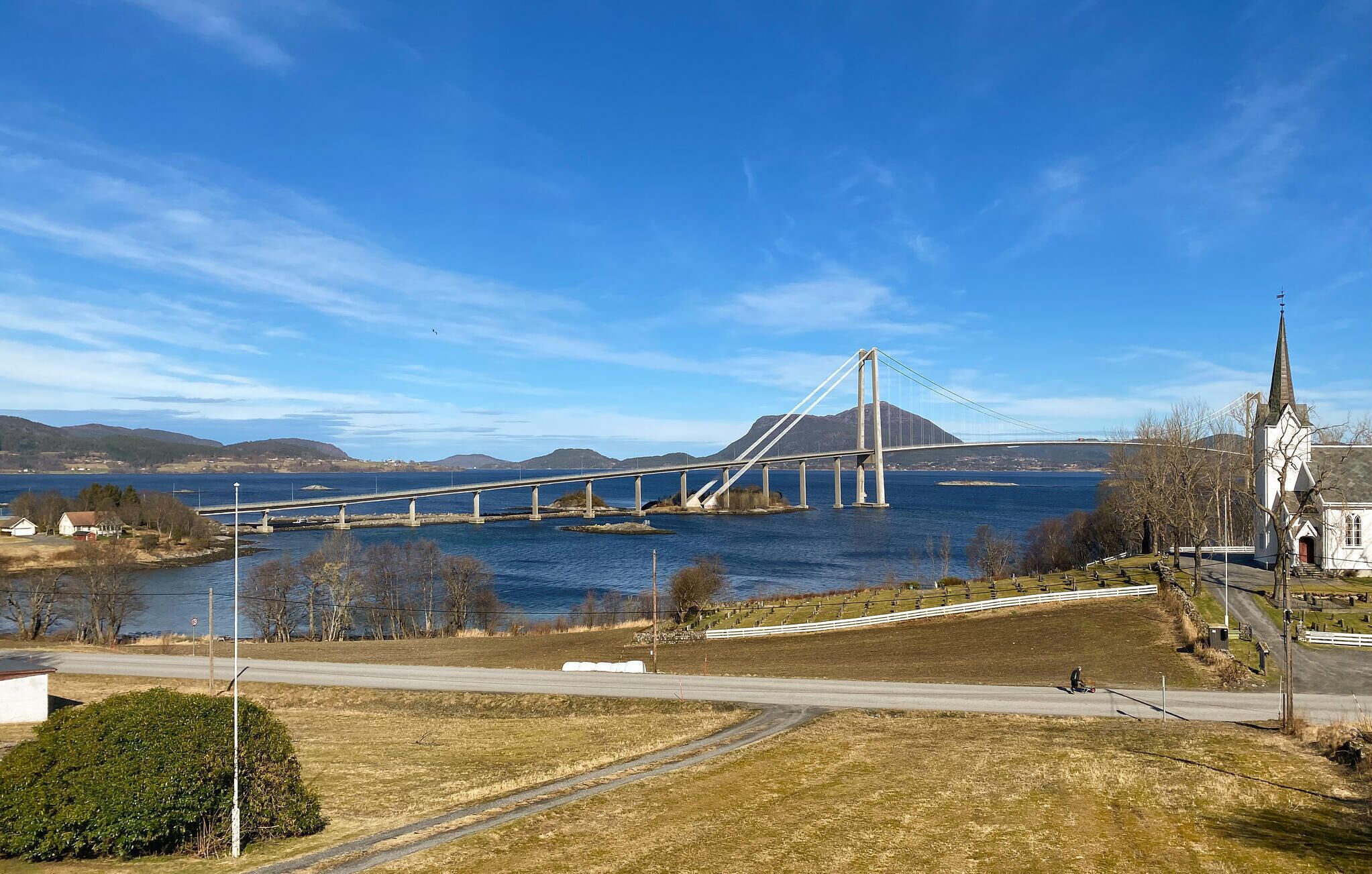 Un pont enjambant une étendue d’eau, avec une église et une route au premier plan.