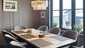 Un comedor con una mesa de madera, sillas tapizadas en gris, una araña y cuadros en la pared.