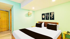 A hotel room with a bed, a wooden door, a nightstand, and wall art. - Deluxeameerpet Balkampet Road (Hyderabad)