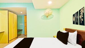 A bedroom with a bed, a bedside table, a wall-mounted fan, and a wardrobe. - Deluxeameerpet Balkampet Road (Hyderabad)
