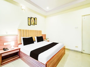 A hotel room with a bed, bedside table, lamp, and wall-mounted artwork. - Deluxe With Twin Bedred Hills Lakdikapul (Hyderabad)
