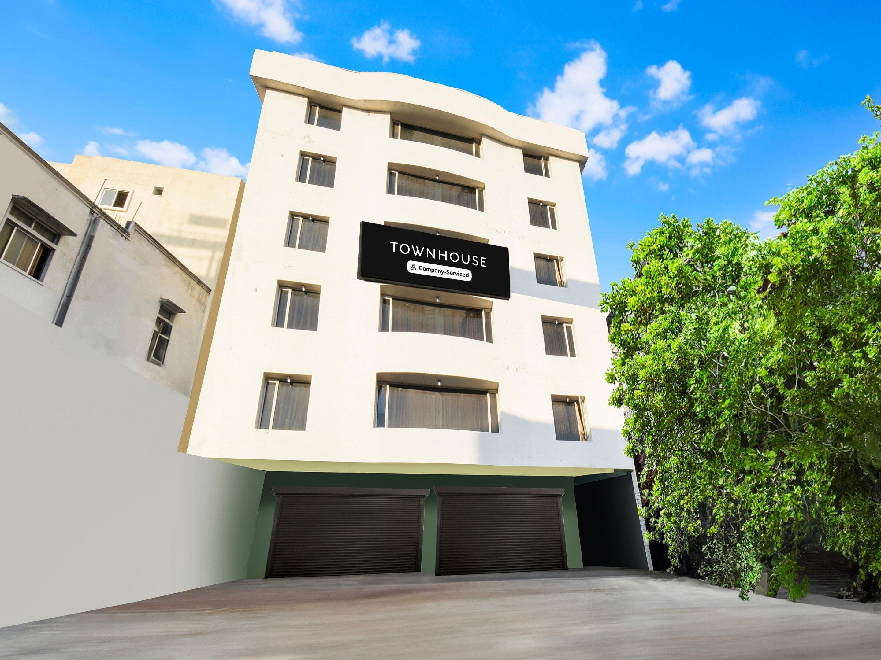 A multi-story building with a sign reading 'TOWNHOUSE Company Serviced.'