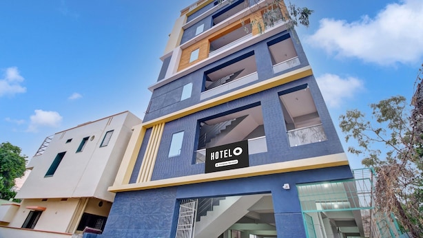Un hôtel à plusieurs étages, doté d’une enseigne « HÔTEL » bien visible, de balcons et d’une architecture moderne.
