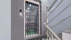 Un ascenseur doté d’un écran numérique, d’une grille métallique et d’une main courante en acier inoxydable.