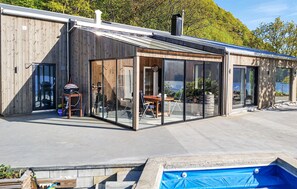 A modern building with large glass doors, a wooden exterior, and a swimming pool. - Lovely home in Farsund (Farsund)
