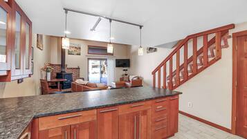 Une cuisine dotée de plans de travail en granit, d’armoires en bois et d’un escalier en bois.