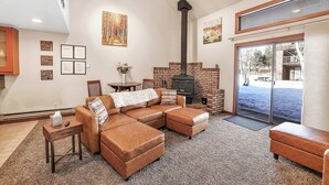 A cozy living room with a sectional sofa, a fireplace, and a large window.